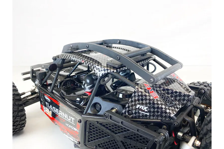 A T-Bone Racing external roll cage installed on a 1/10 scale Losi Lasernut RC truck, featuring a black plastic frame over the vehicle's cabin.