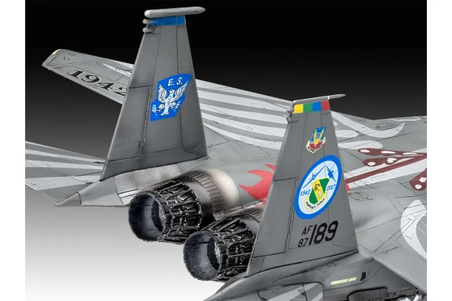 Close-up of the rear section of a 1/72 scale F-15E Strike Eagle model, showing the twin engine exhausts, vertical stabilizers with commemorative decals, and grey camouflage.