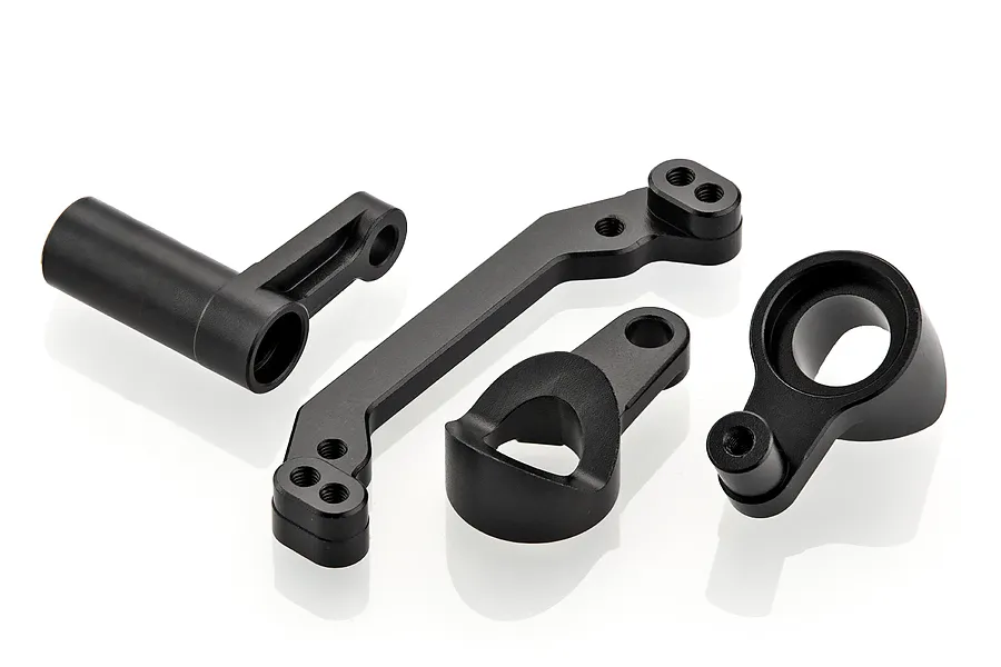 A set of four black aluminium RC car steering components including a servo saver arm and bell crank parts on a white background.