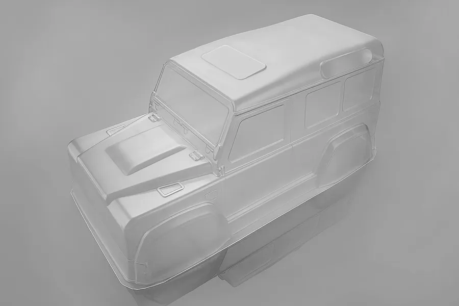 A clear, unpainted 1/16 scale RC crawler body shell, viewed from a high angle against a plain grey background.