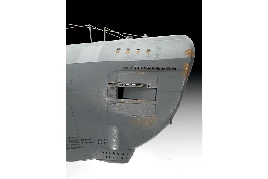 Close-up of the bow section of a painted plastic model submarine, showing grey hull plating with weathering effects and rust details.