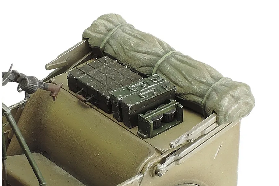 Close-up of the rear cargo area of a painted 1/35 scale German military vehicle model, showing a rolled tarp and various supply crates.