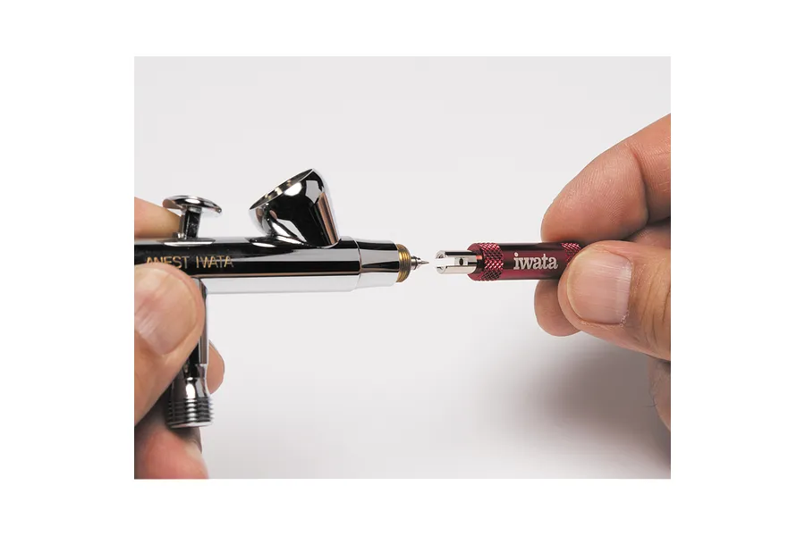 A person using an Iwata nozzle wrench to remove the nozzle from an Anest Iwata airbrush.