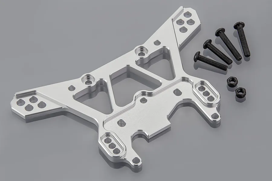 A silver aluminium RC shock tower with multiple mounting holes, accompanied by four black screws and two black nuts on a grey background.