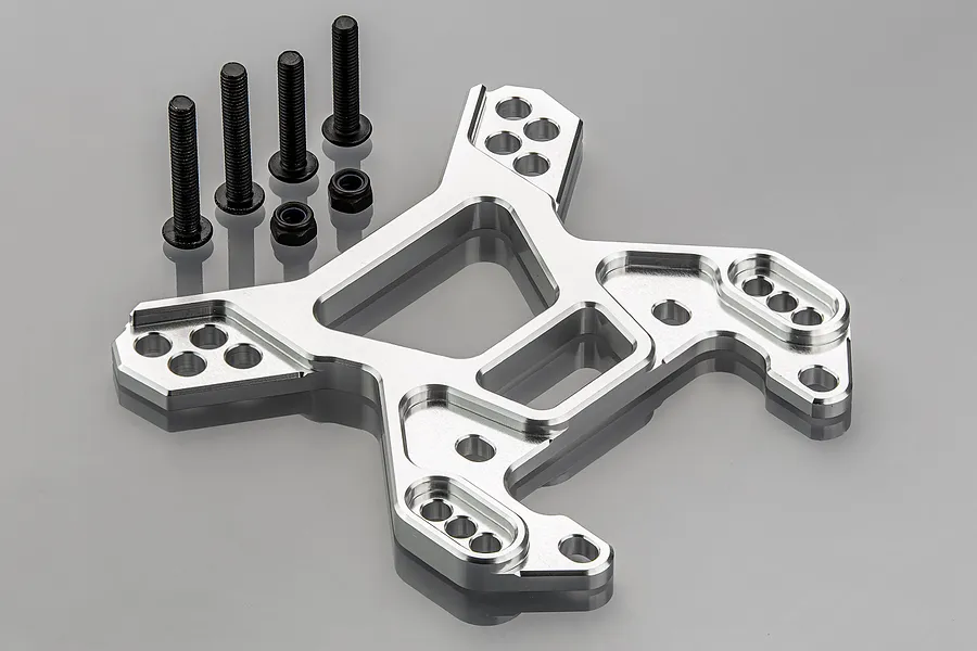 A silver aluminium front shock tower for an RC vehicle, accompanied by four black bolts and two black nuts on a grey background.