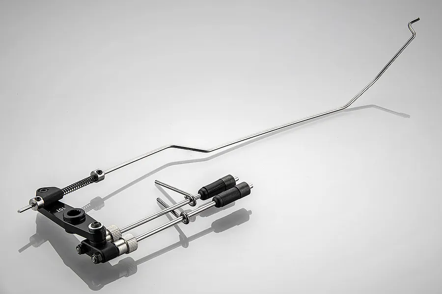 Rovan 5IVE-T 71cc throttle and brake linkage set featuring metal rods, black plastic components, and a spring on a light grey background.
