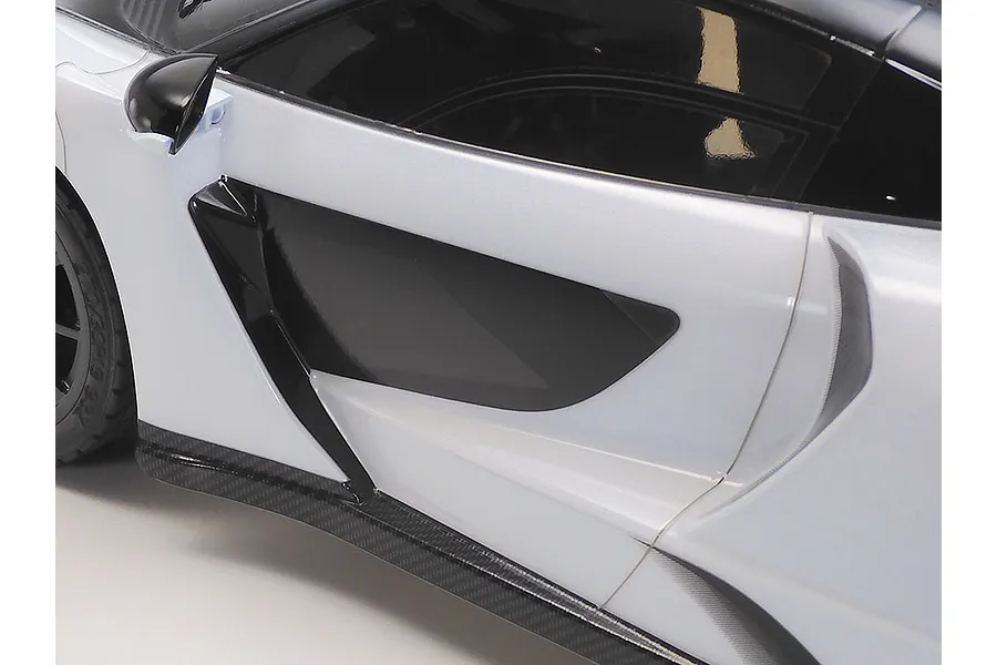 Close-up side view of a white and black McLaren Senna RC car body shell showing the door panel, side intake, and side skirt.
