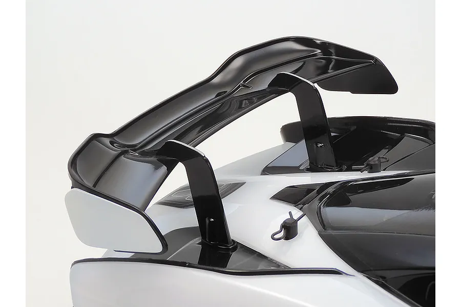 Close-up view of the rear wing and body shell of a Tamiya McLaren Senna RC car, showing the black spoiler mounted on the white body.