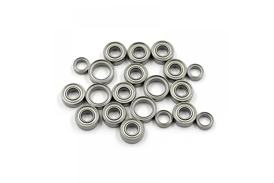A collection of twenty metal ball bearings of varying sizes scattered on a white background.