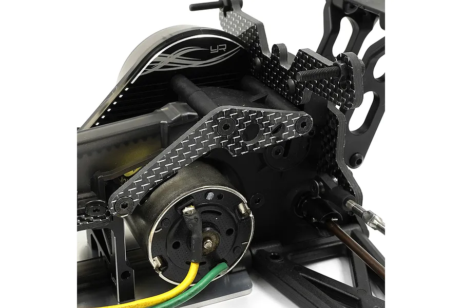 Close-up of a Yeah Racing carbon fiber gear box brace installed on a Kyosho Optima Mid RC chassis, showing the motor and surrounding components.