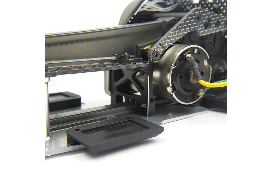 Close-up of a black aluminium Yeah Racing upper deck brace installed on an RC car chassis with carbon fibre components.