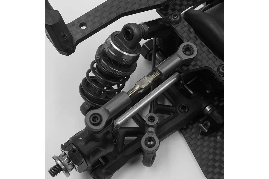 Close-up of an RC car suspension assembly featuring a silver titanium turnbuckle installed on an Xpress Arrow AT1 chassis.