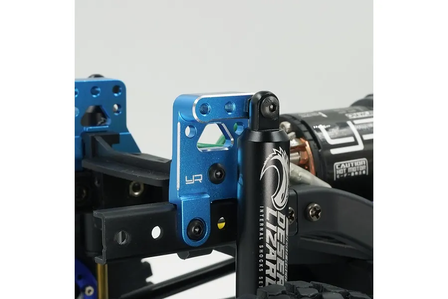 Blue anodized aluminum shock mount installed on an RC chassis next to a black Desert Lizard shock absorber.