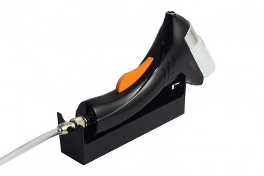 Sparmax Flyer airbrush resting in its black plastic stand with an air hose connected to the base.
