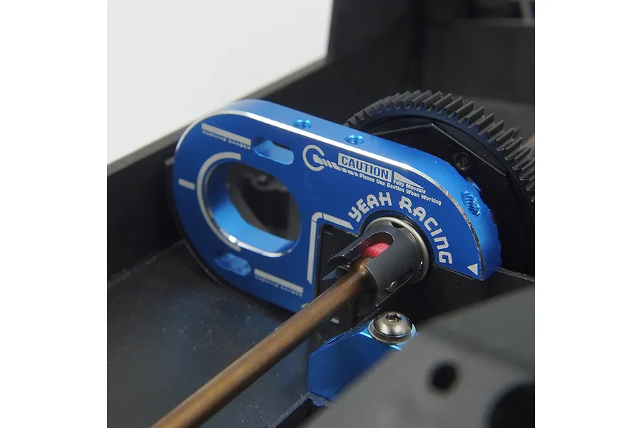 A blue anodized aluminium motor mount by Yeah Racing installed on a black RC chassis, showing the motor plate and drive shaft connection.