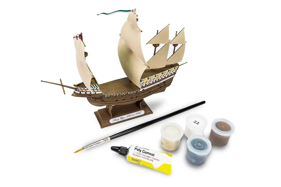 Assembled Airfix Mary Rose model ship on a stand with a paintbrush, tube of poly cement, and four small pots of paint.