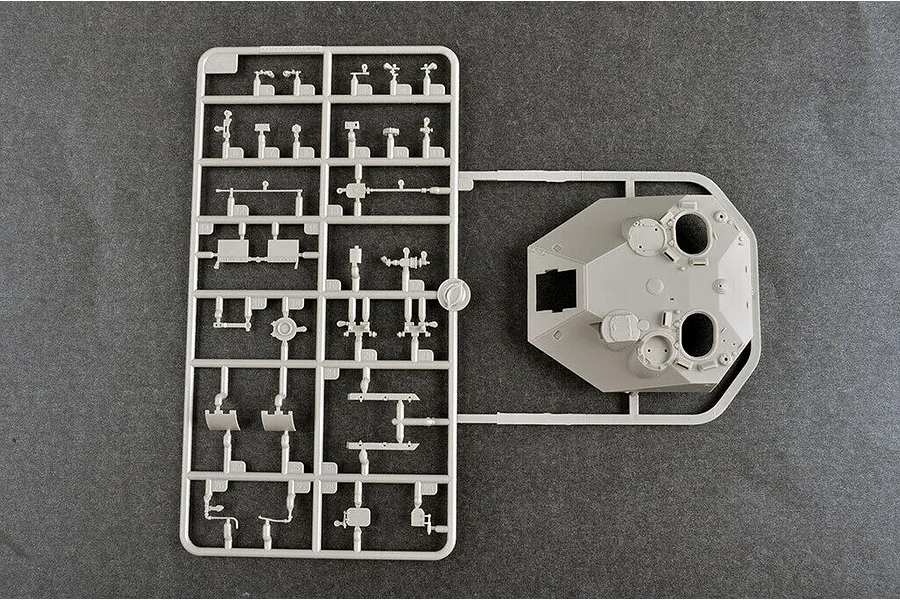 A grey plastic model kit sprue containing various small tank parts and a large turret section for a 1/35 scale military vehicle model.