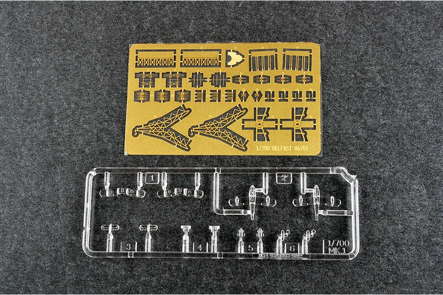 A photo-etched brass fret and a clear plastic sprue for a 1/700 scale model kit of HMS Belfast.