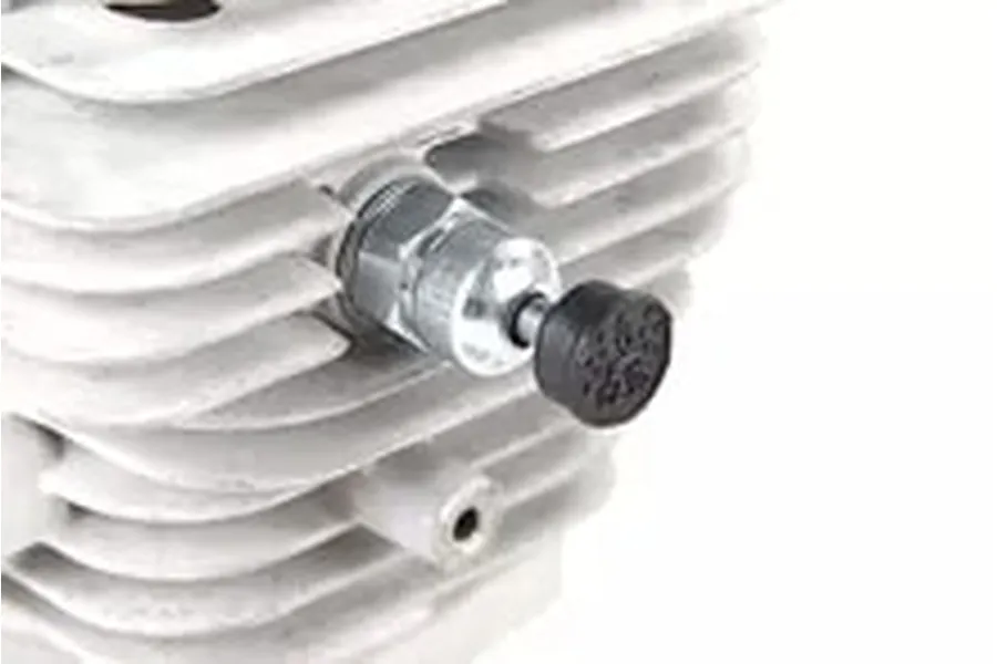 A close-up of a pressure reducing valve installed on a finned metal RC engine cylinder head.