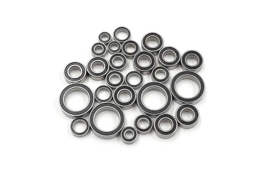 A collection of various sized metal ball bearings with black rubber seals, arranged in a pile on a white background.