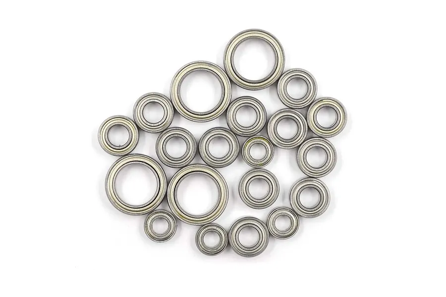 A collection of various sizes of metal shielded ball bearings arranged on a white background.