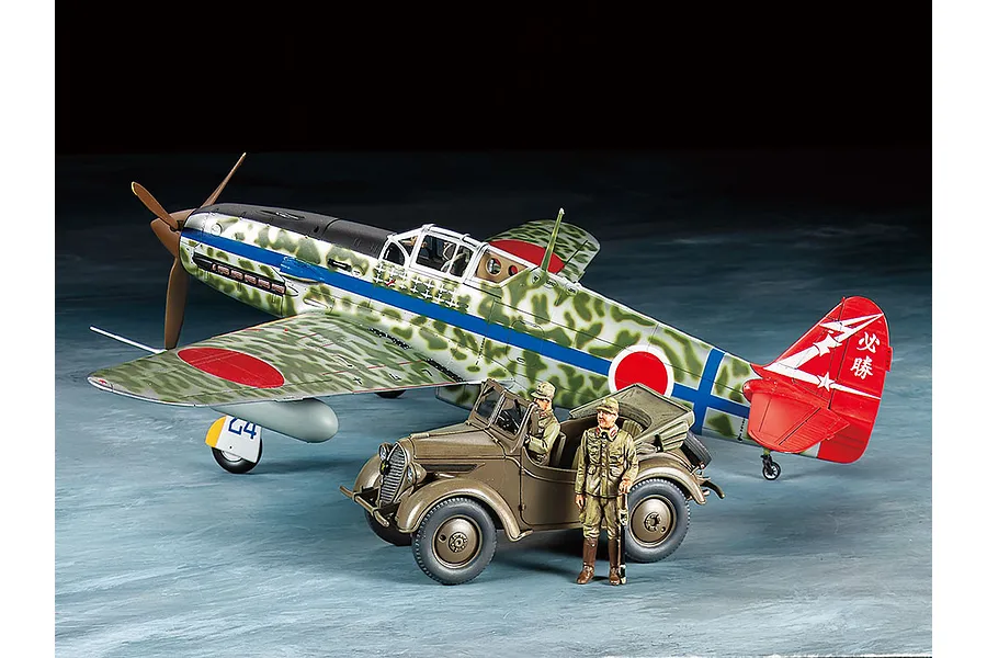 A 1/48 scale model of a Kawasaki Ki-61-Id Hien aircraft with camouflage paint, alongside a Kurogane 4x4 light vehicle and two painted pilot figures.