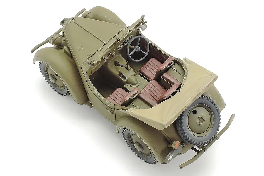 A high-angle studio shot of a 1/48 scale model of a Kurogane 4x4 light vehicle, painted in olive drab with brown interior seats.