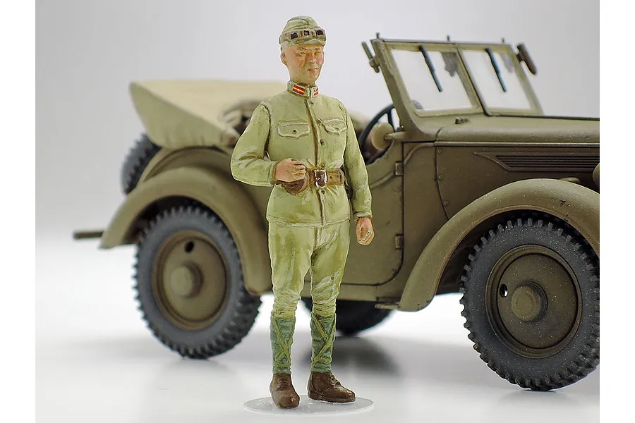 A painted 1/48 scale plastic model figure of a Japanese military officer standing in front of a Kurogane 4x4 light vehicle model.