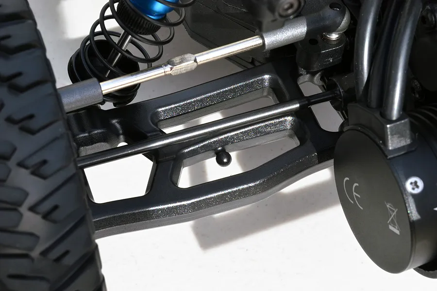 Close-up of a black RPM rear suspension arm installed on an RC vehicle, showing the arm's structure, drive shaft, and surrounding suspension components.
