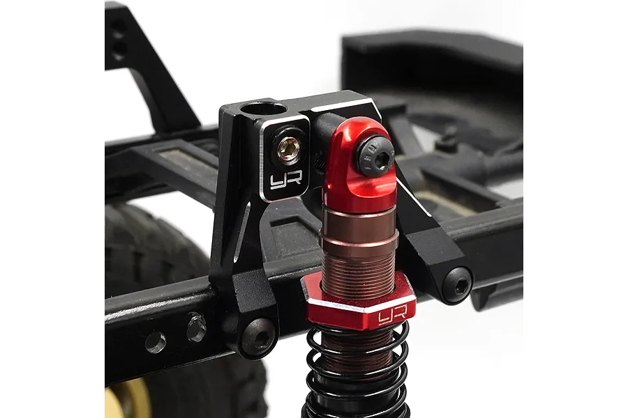 Close-up of a black aluminium shock mount installed on an RC car chassis with a red and bronze shock absorber attached.
