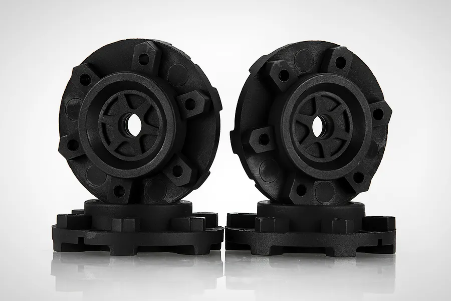 Four black plastic RC wheel hex adapters arranged in a studio setting against a white background.