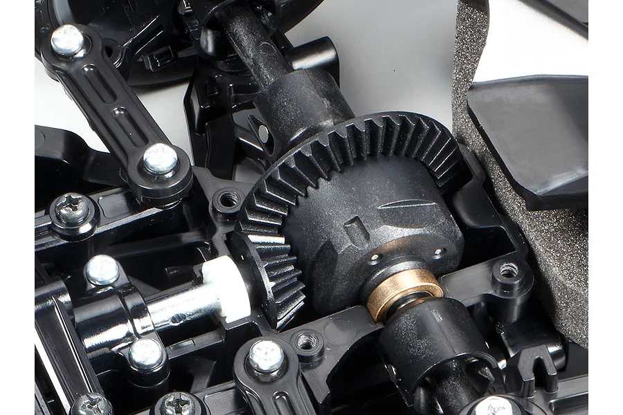 Close-up of the Tamiya TT-02 chassis differential and drivetrain components showing plastic gears, metal screws, and a bronze bushing.