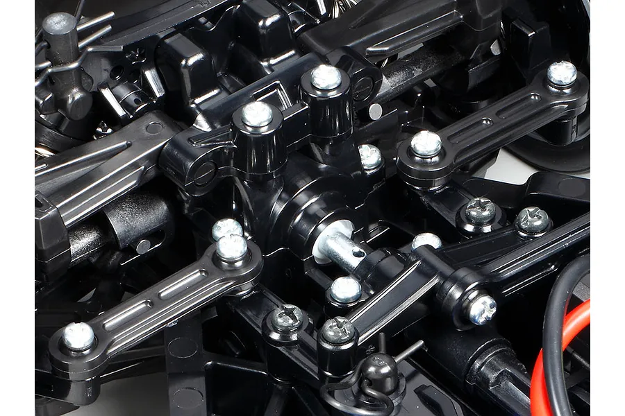 Close-up view of the black plastic suspension and steering components of a Tamiya TT-02 RC car chassis.