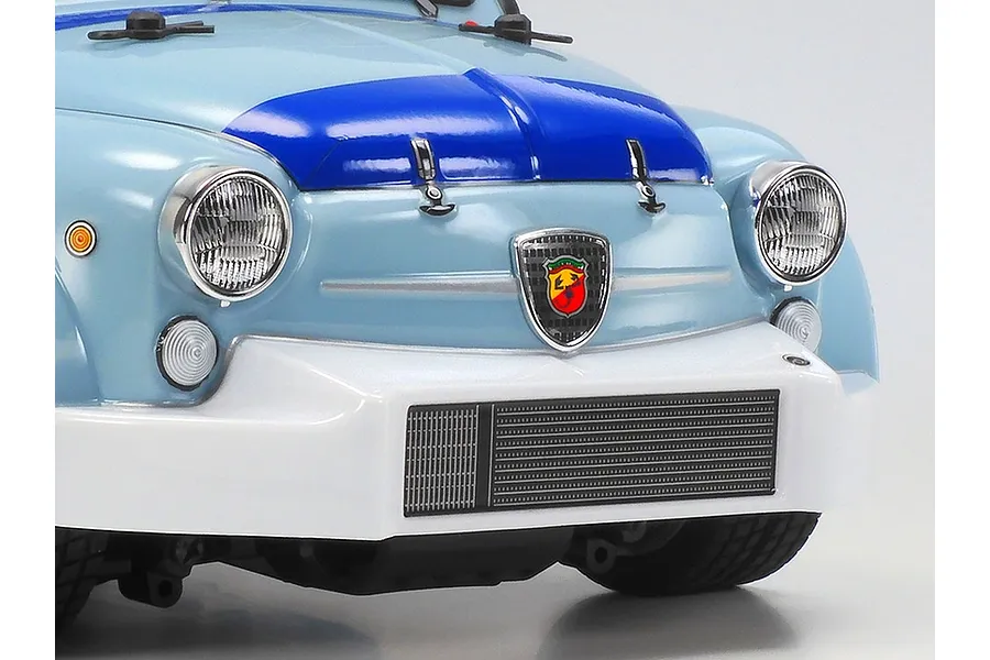 Close-up of the front of a light blue Tamiya Fiat Abarth 1000TCR RC car body, showing the hood, headlights, Abarth emblem, and white front bumper.