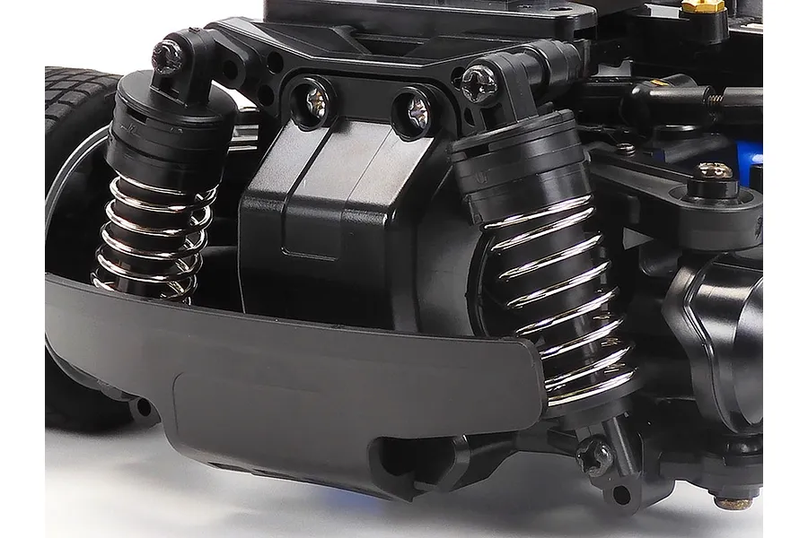 Close-up of the front suspension and bumper assembly on a Tamiya MB-01 RC car chassis.