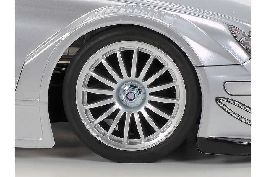 Close-up of the front wheel and fender of a silver Tamiya Mercedes-Benz CLK-AMG RC touring car model.