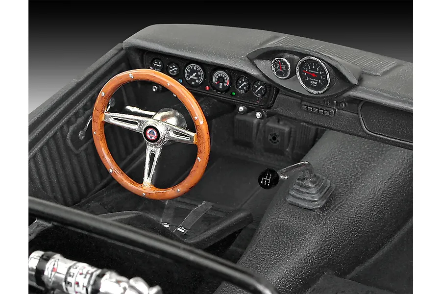 Close-up of the detailed interior of a 1/24 scale model car, featuring a wood-rimmed steering wheel, dashboard gauges, and a manual gear shifter.