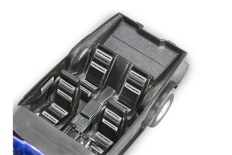 Top-down view of the black plastic interior tub for a 1/24 scale 1985 Chevy Camaro model kit, featuring molded seats with Camaro branding decals.