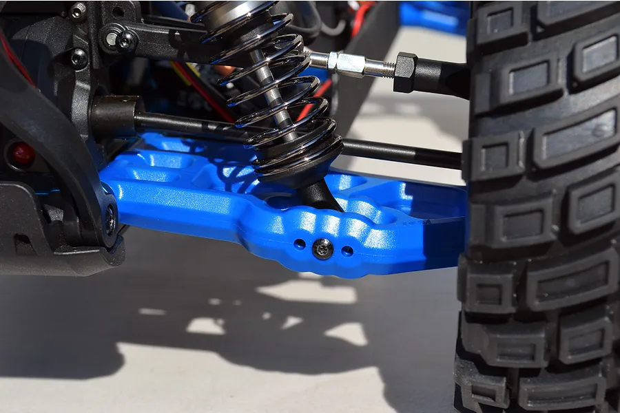 Close-up of a bright blue RPM rear suspension arm installed on an RC vehicle, showing the shock absorber and tire.