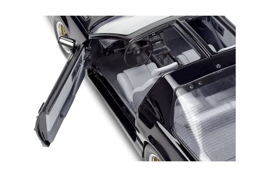 High angle close-up of the interior of a black 1/16 scale Pontiac Firebird model car with the driver side door open.