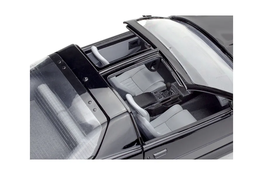 High-angle view of the interior of a black 1987 Pontiac Firebird GTA model car, showing grey seats, center console, and T-top roof panels.
