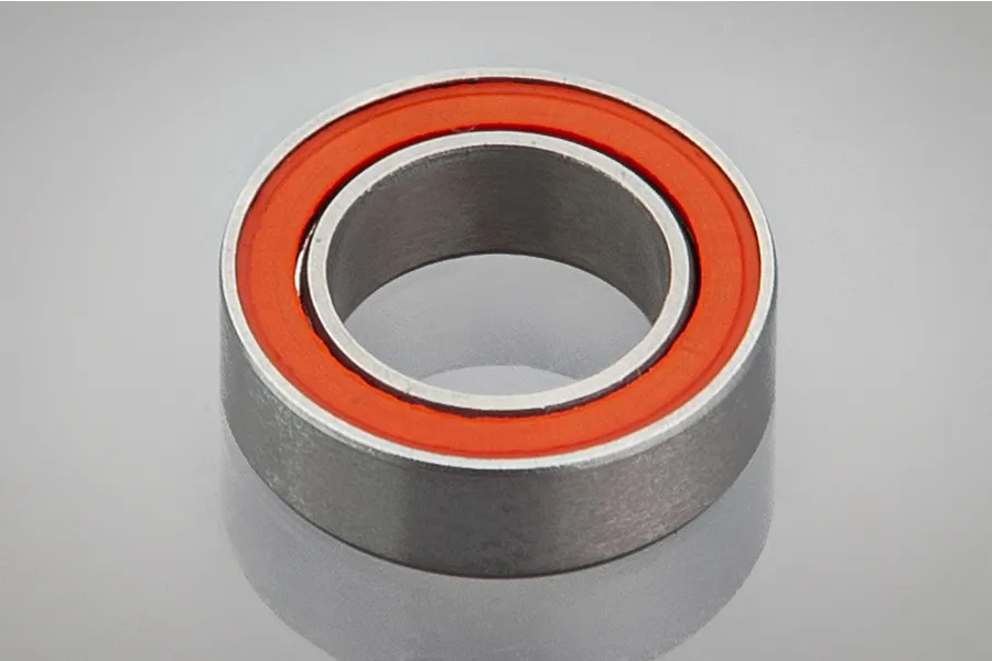 A single metal ball bearing with an orange rubber seal, shown in a studio product shot against a light grey background.