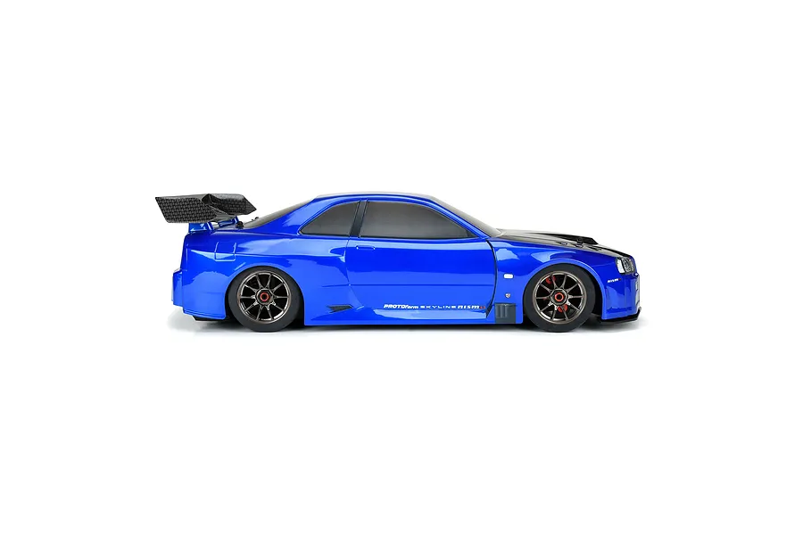 Side profile of a blue Protoform Nissan Skyline GT-R R34 RC car body shell with a black hood and rear wing on a white background.