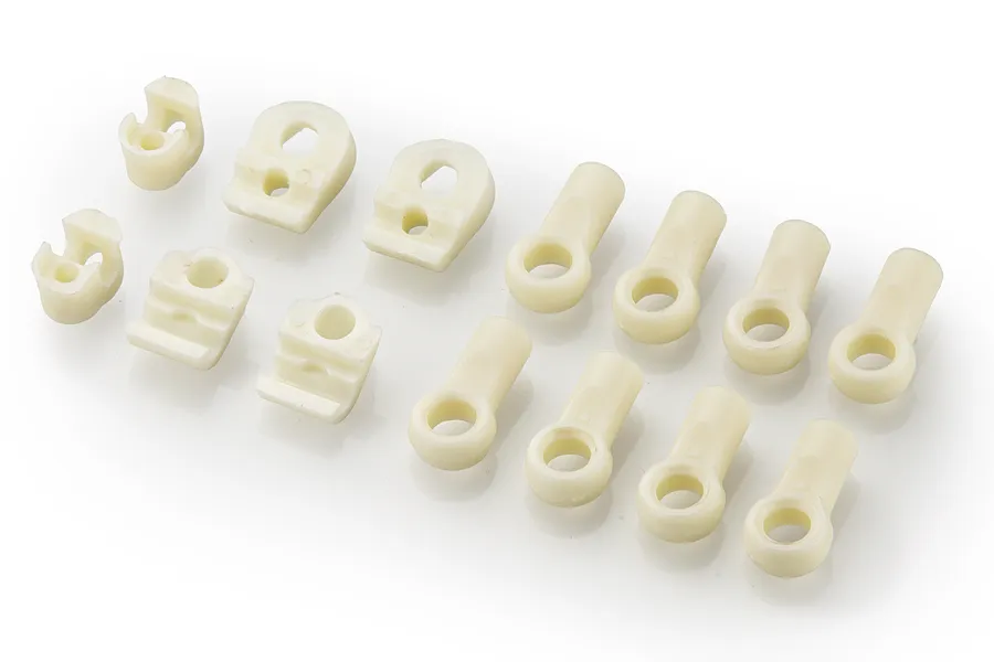 A set of white nylon RC sway bar mounts and rod ends arranged on a white background.