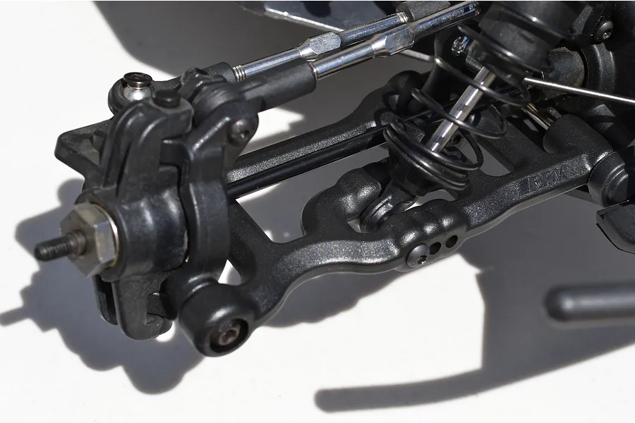 Close-up of a black RPM RC front suspension arm installed on an RC vehicle chassis.