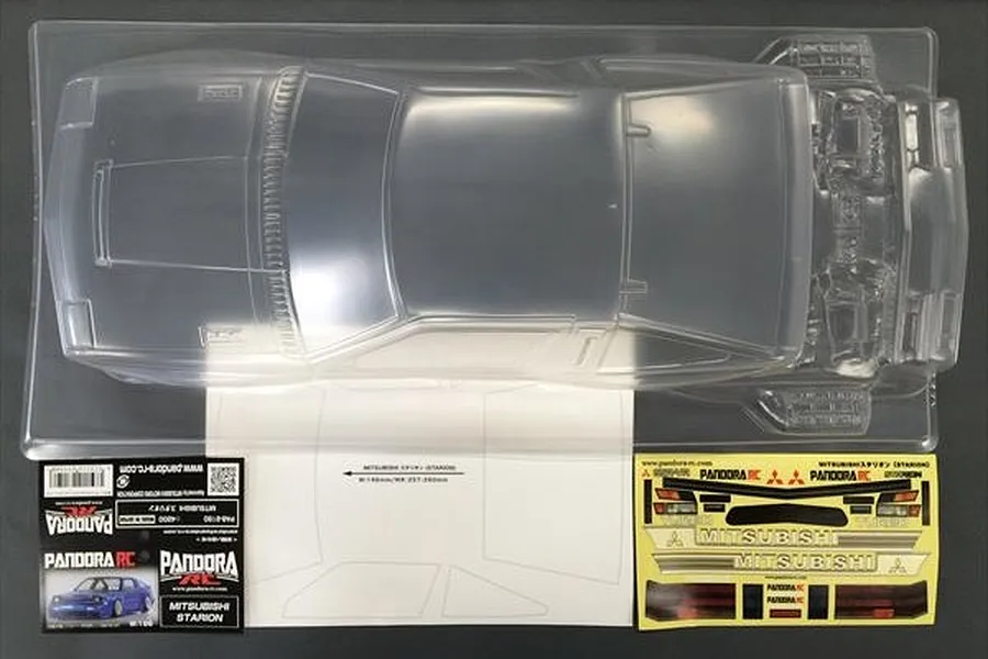 Top-down view of a clear, unpainted 1/10 scale Mitsubishi Starion RC car body shell by Pandora RC, including decal sheet and masking film.