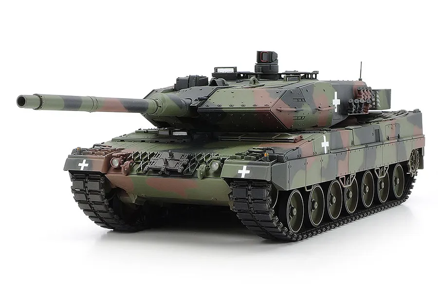 A fully assembled and painted Tamiya 1/35 scale Leopard 2 A6 tank model with a camouflage pattern and white cross markings on a white background.