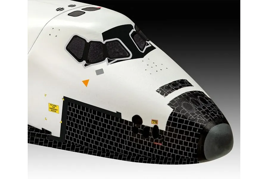 Close-up of the nose section of a white and black space shuttle model kit, showing cockpit windows and thermal tile detailing.
