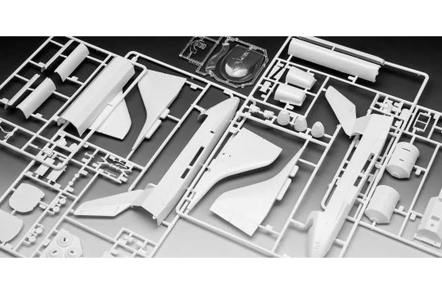 White plastic model kit sprues for a space shuttle, including fuselage parts, wings, and a clear canopy piece.