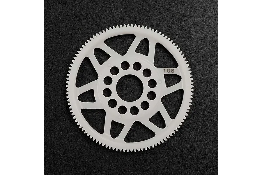 A white Delrin 108T spur gear for RC cars, featuring a spoked design and central mounting holes, set against a dark textured background.